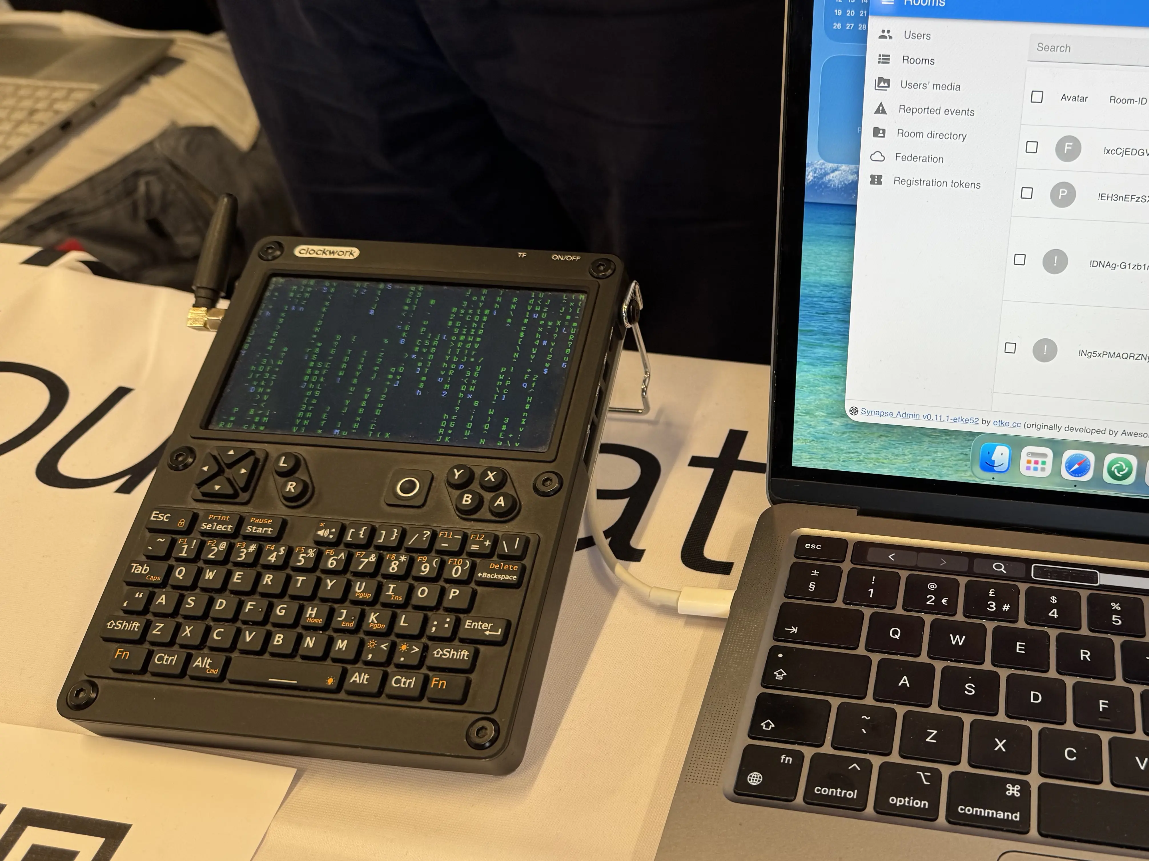 A picture of t-shirts stacked on a booth. There seems to be a lot of activity around the booth.